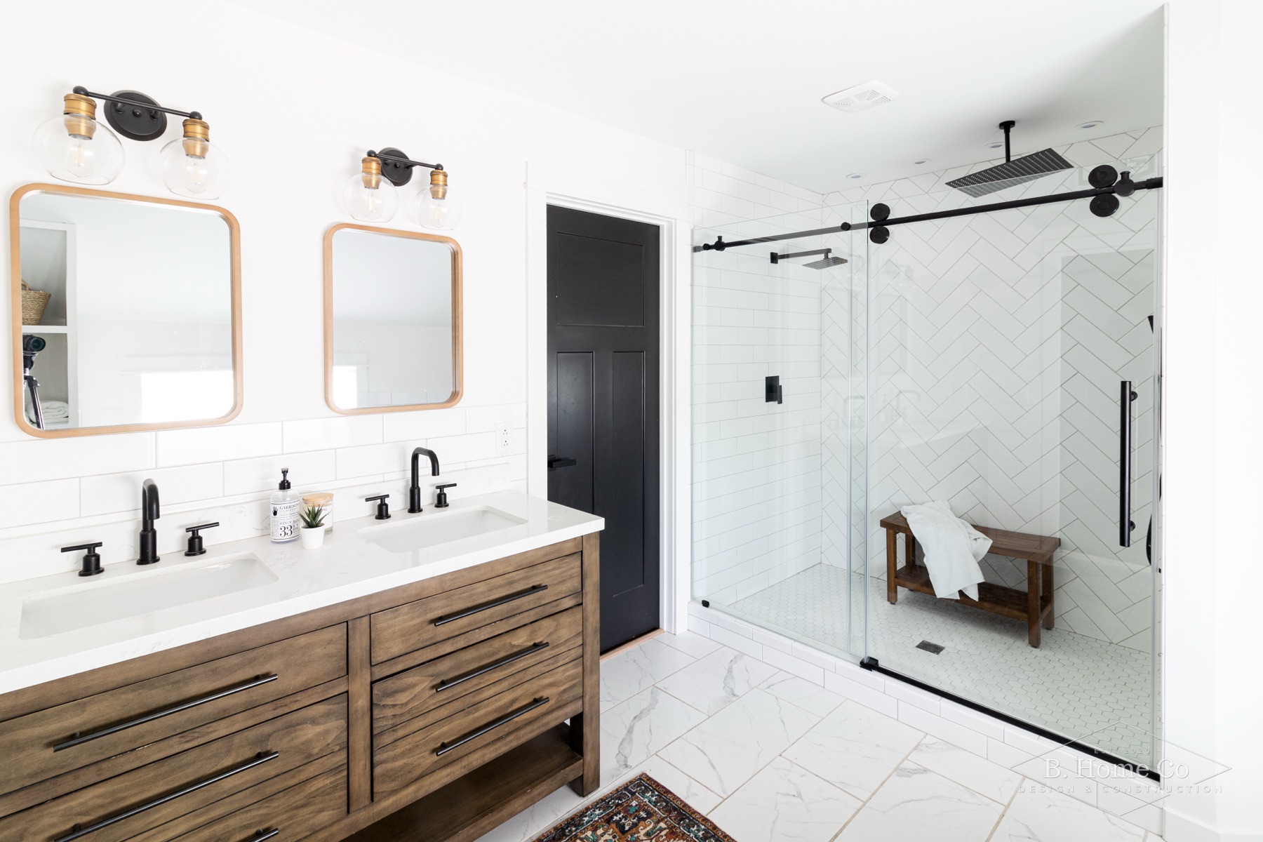 Primary bathroom with double wood vanity, black fixtures, and glass shower