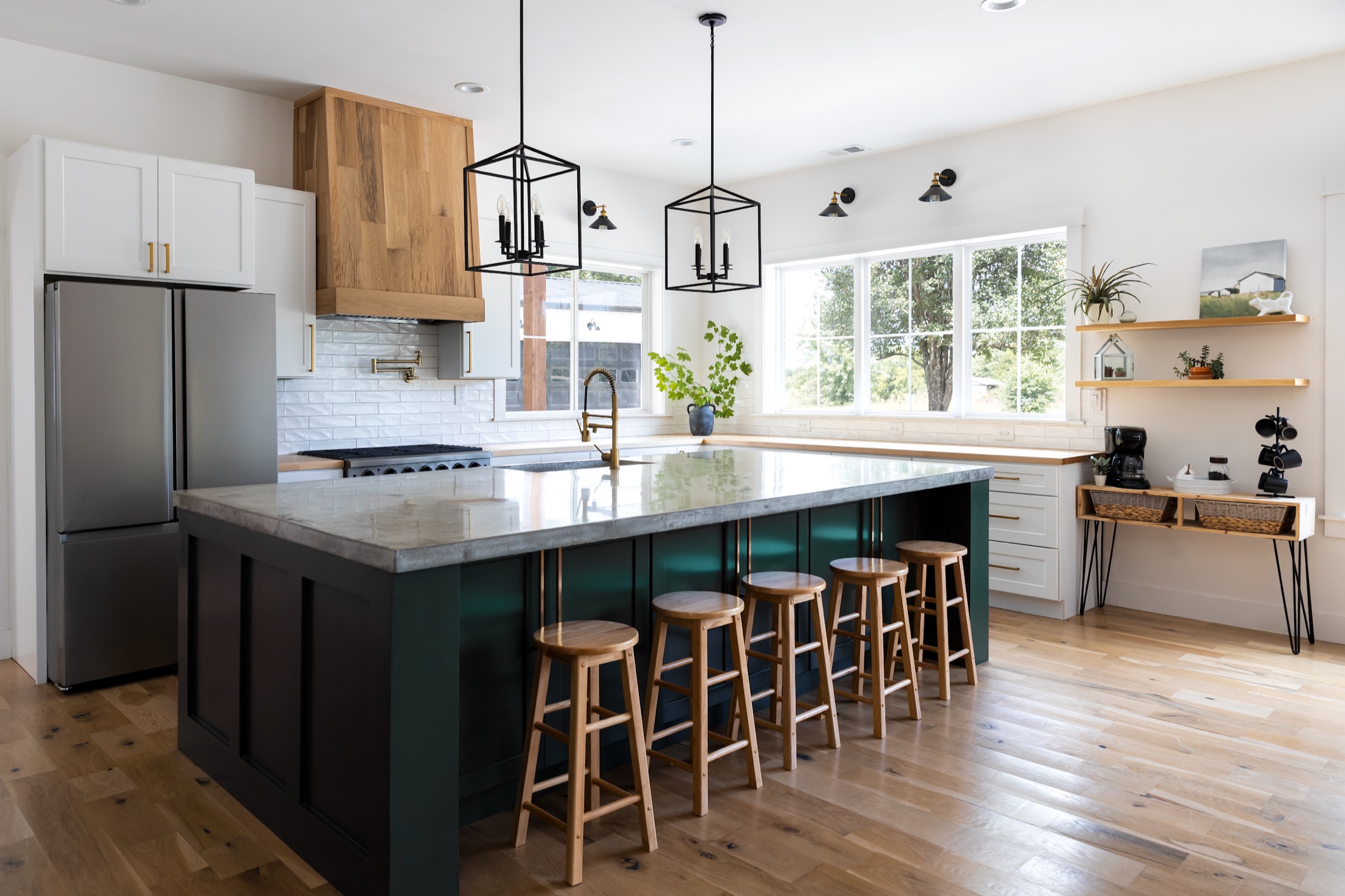 Renovated farmhouse kitchen with a deep green island, marble waterfall counter, and custom wood range hood