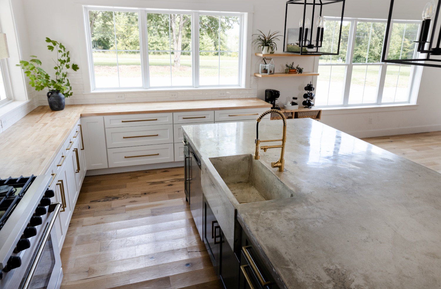 Kitchen with green island, marble counters, black pendant lights and white tile